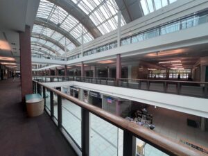 Unutrašnjost tržnog centra sa staklenim svodom i gornjom galerijom